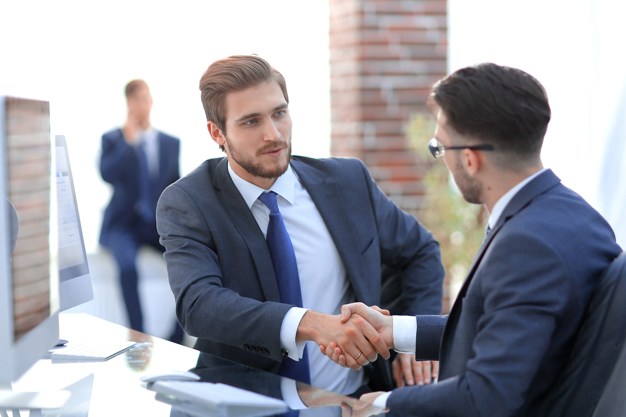 Image of two young businessmen interacting at meeting in office